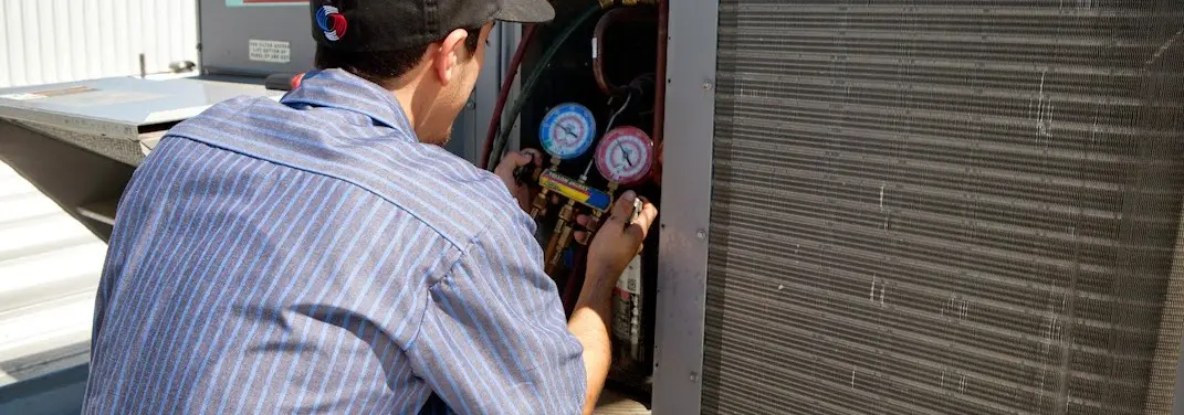 HVAC technician servicing a condenser unit in Holbrook
