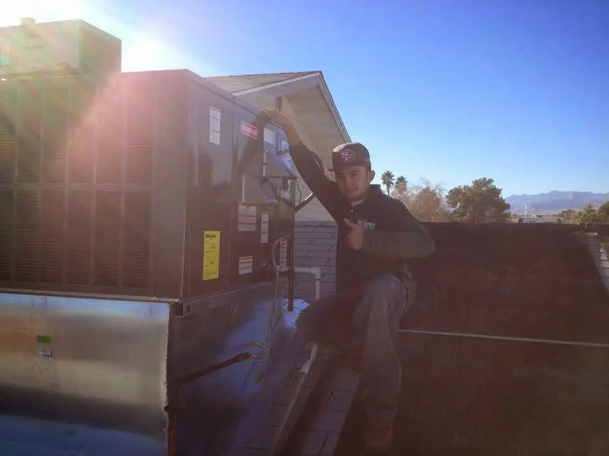 HVAC technician performing Air Duct Repair on a rooftop unit in Holbrook